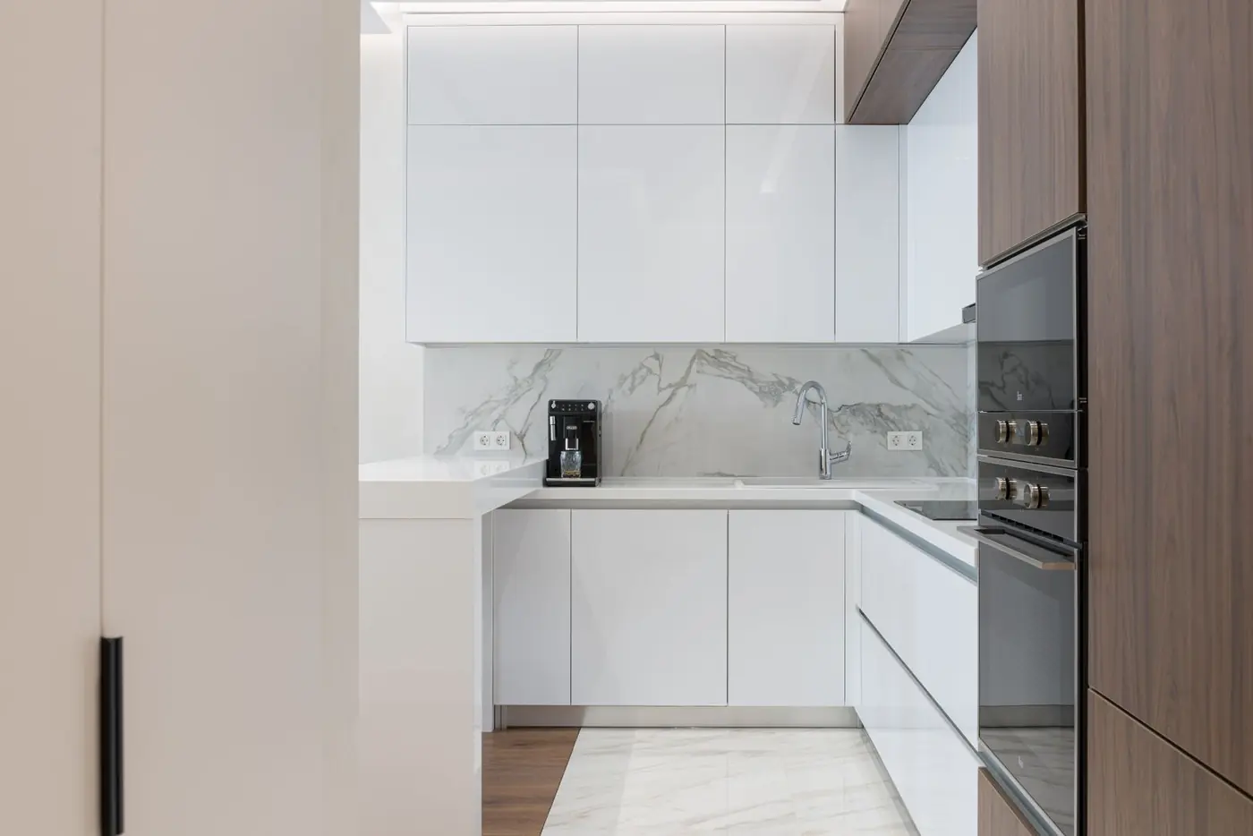 Cocina lineal contemporánea con hornos empotrados y cubierta de piedra
